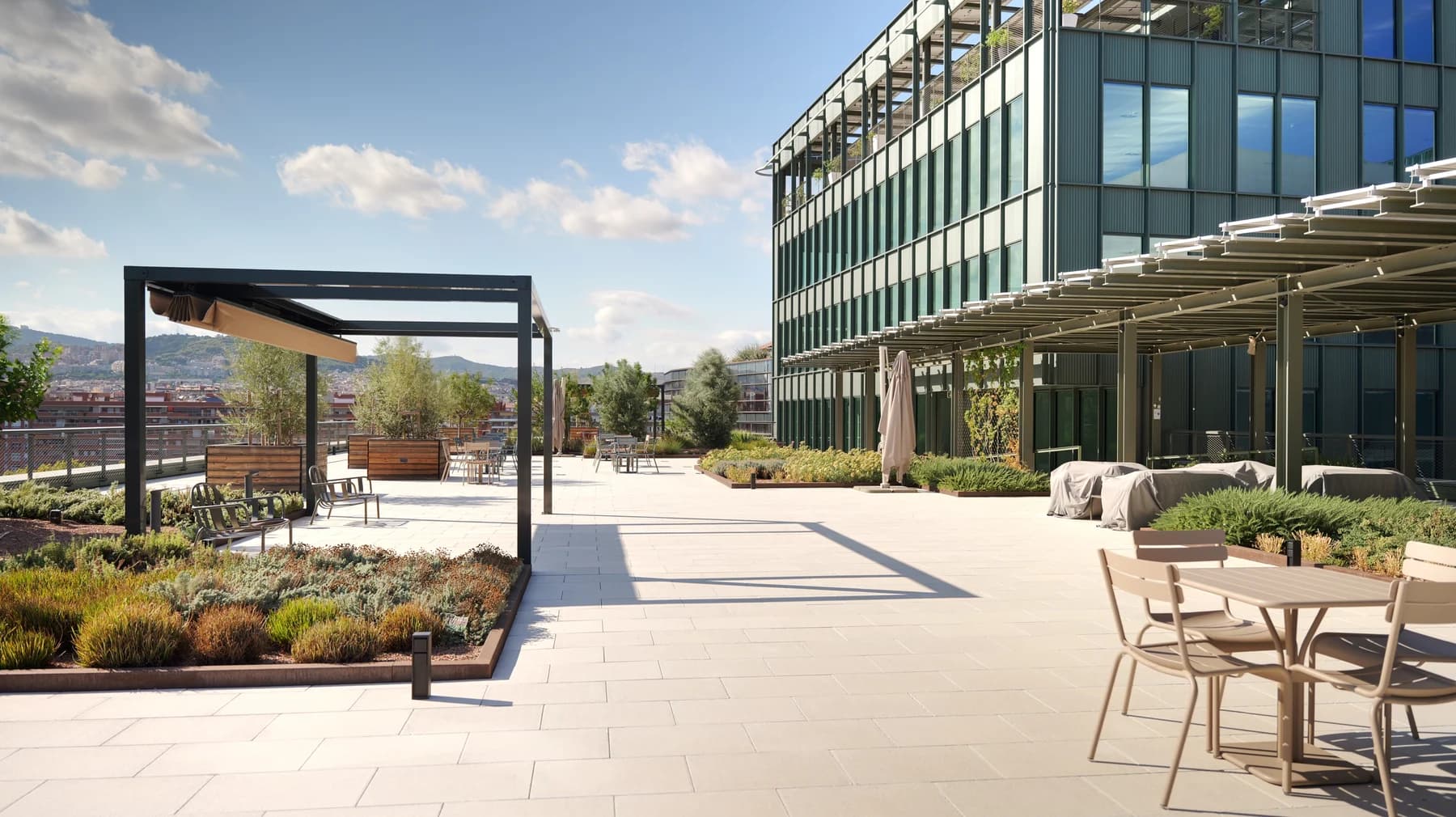 Planted rooftop terrace with outdoor tables, a pergola and the glass-fronted Bilbao 128 building