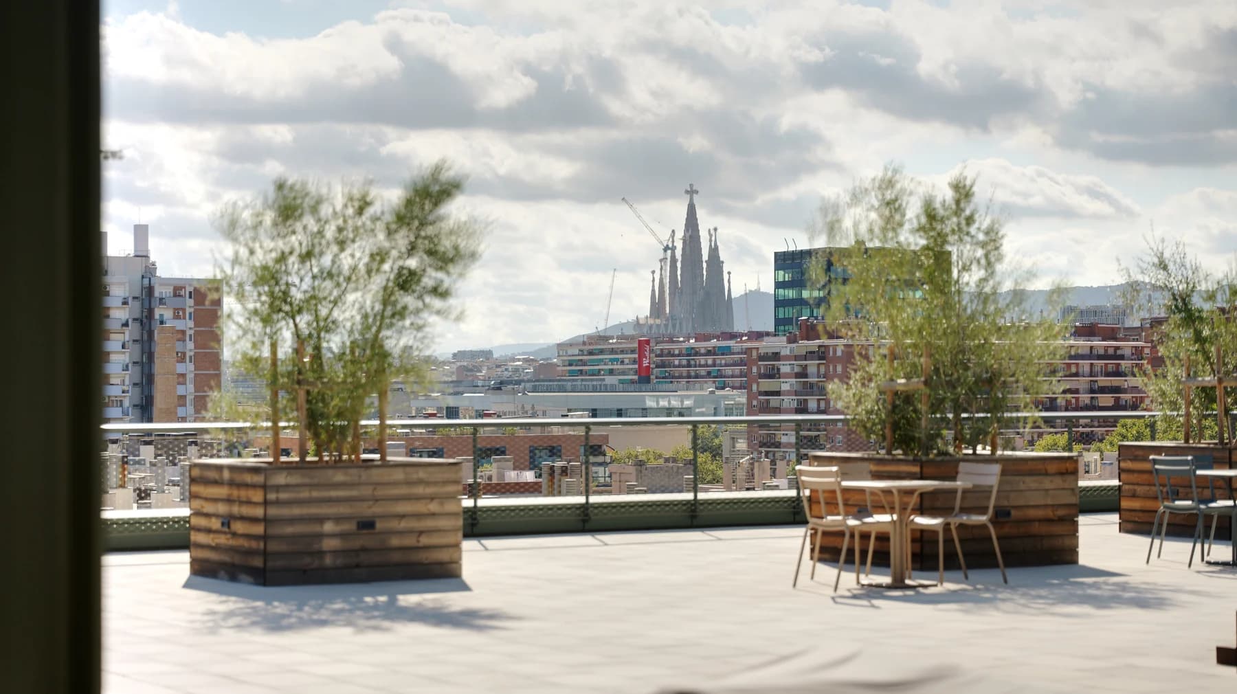 Rooftop terrace with wooden planters and outdoor seating overlooking Barcelona and the Sagrada Família